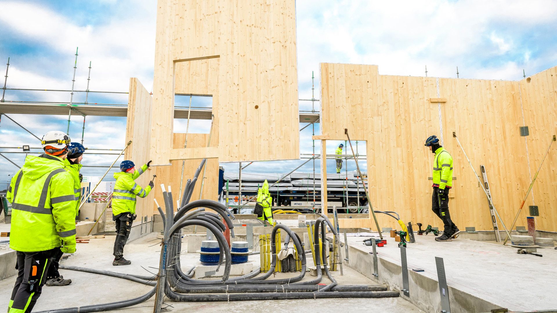 Byggeplass der arbeidere monterer prefabrikkerte CLT-massivtreelementer på et fundament.